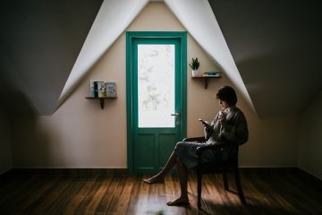 Mulher sentada em cadeira em frente a uma porta